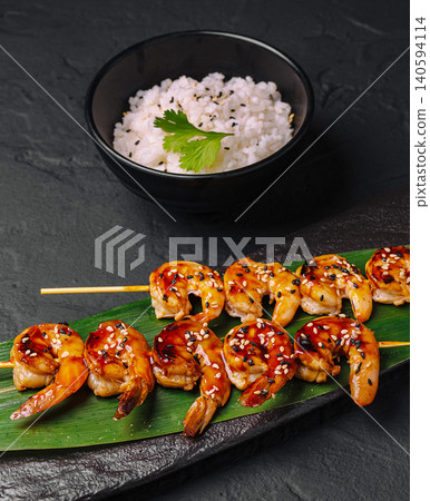 Grilled shrimp skewers with rice served on a leaf in a kitchen Grilled shrimp skewers with rice served on a leaf in a kitchen 140594114
