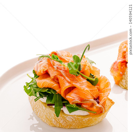 Fresh salmon on bread with greens served on a white plate Fresh salmon on bread with greens served on a white plate 140594121