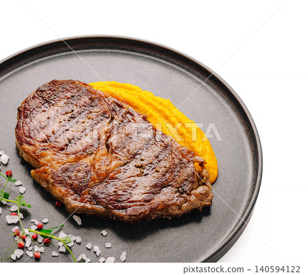 Steak served with mashed carrots and seasoning on a black plate Steak served with mashed carrots and seasoning on a black plate 140594122