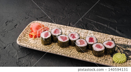 Sushi rolls served on a plate with wasabi and ginger on a dark table Sushi rolls served on a plate with wasabi and ginger on a dark table 140594131