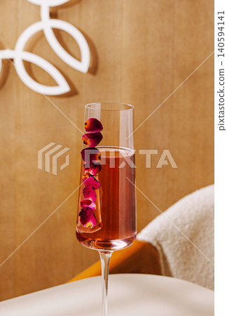 champagne with rose petals in a glass on a simple table with light background 140594141