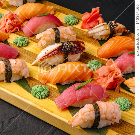 Sushi platter with various types of sushi and garnishes on a wooden board Sushi platter with various types of sushi and garnishes on a wooden board 140594166