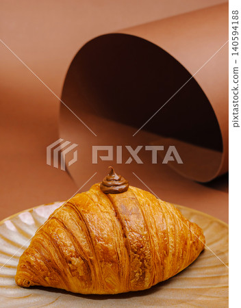 Fresh croissant on a plate with chocolate cream in a simple setting Fresh croissant on a plate with chocolate cream in a simple setting 140594188