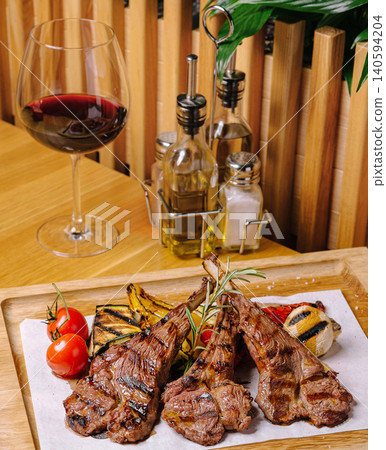 Grilled meat served with wine and vegetables in a restaurant setting 140594204