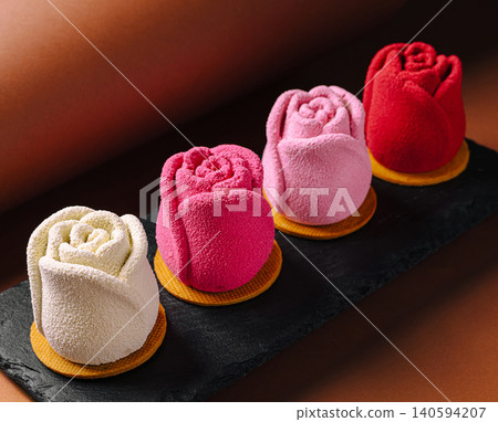 Colorful rose-shaped desserts on a black plate served on a brown surface 140594207