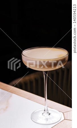 Cocktail served on a wooden table in a cozy bar space during the evening Cocktail served on a wooden table in a cozy bar space during the evening 140594213