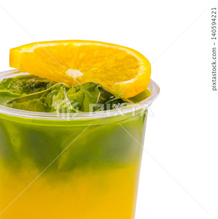 Refreshing drink with layers of orange and green in clear cup served cold 140594221