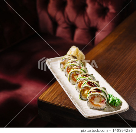 Fresh sushi rolls served on a plate beside a deep red sofa in a restaurant Fresh sushi rolls served on a plate beside a deep red sofa in a restaurant 140594286
