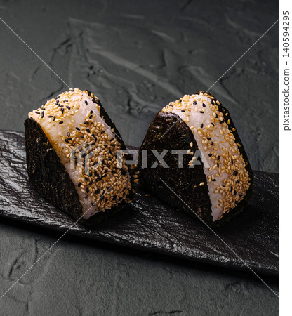 Enjoying rice balls on a dark plate with soy sauce on the side during a meal Enjoying rice balls on a dark plate with soy sauce on the side during a meal 140594295