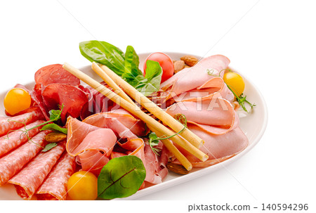 Lunch platter with cold cuts, greens, and snacks on a white background Lunch platter with cold cuts, greens, and snacks on a white background 140594296
