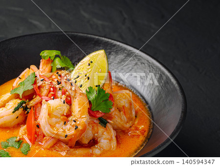 Shrimp dish with lime and herbs in black bowl on dark background Shrimp dish with lime and herbs in black bowl on dark background 140594347