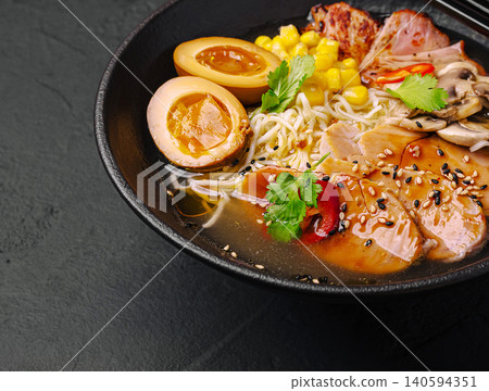 Delicious bowl of ramen with eggs and corn served in a dark setting Delicious bowl of ramen with eggs and corn served in a dark setting 140594351