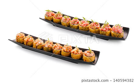 Delicious sushi rolls served on black plates at a restaurant setting Delicious sushi rolls served on black plates at a restaurant setting 140594382