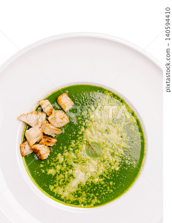 Spinach soup with pieces of crackers and cheese topping in a modern bowl Spinach soup with pieces of crackers and cheese topping in a modern bowl 140594410