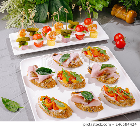 Food display with various appetizers on white plates in a bright setting 140594424