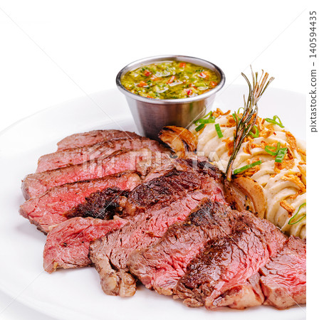 Grilled steak served with sides on a white plate in a restaurant Grilled steak served with sides on a white plate in a restaurant 140594435
