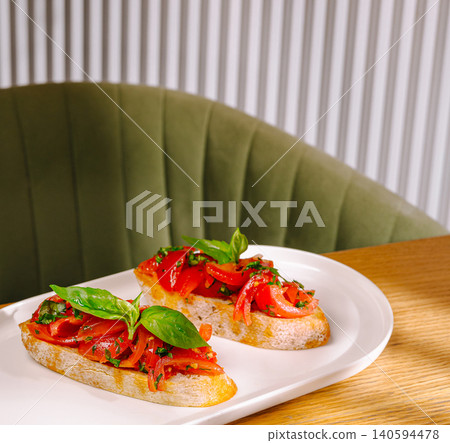Bruschetta is served on a white plate in a cafe setting in the afternoon 140594478