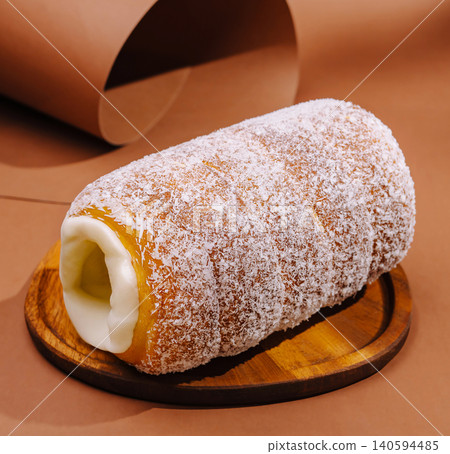 Coconut roll dessert placed on a wooden serving board in a kitchen setting Coconut roll dessert placed on a wooden serving board in a kitchen setting 140594485