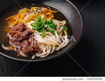 Warm bowl of beef noodle soup with vegetables served in dark bowl Warm bowl of beef noodle soup with vegetables served in dark bowl 140594509