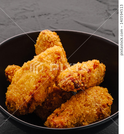 Fried chicken pieces served in a black bowl with a dark background Fried chicken pieces served in a black bowl with a dark background 140594513