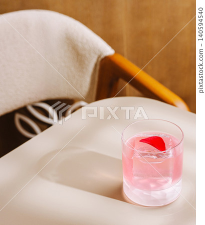 Drink sits on a table next to a chair in a quiet space during the day Drink sits on a table next to a chair in a quiet space during the day 140594540