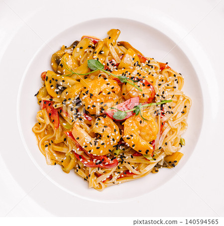 Shrimp and vegetable pasta served on a white plate with seasoning Shrimp and vegetable pasta served on a white plate with seasoning 140594565