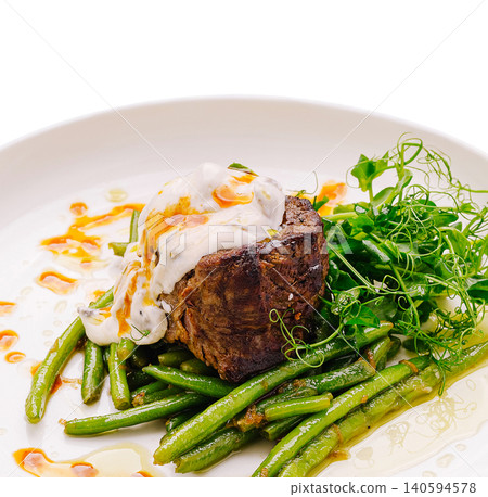 Delicious beef dish served with green beans and sauce in a restaurant setting Delicious beef dish served with green beans and sauce in a restaurant setting 140594578