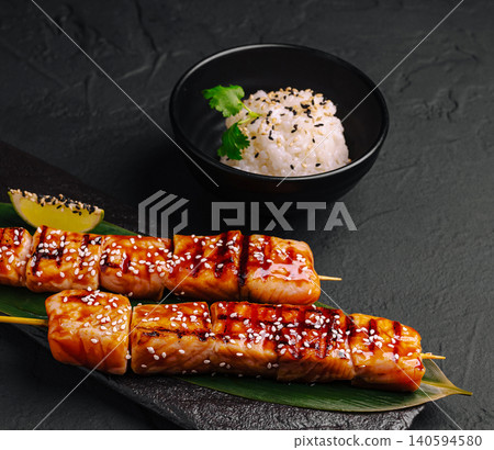 Grilled salmon skewers served with rice and garnished with herbs Grilled salmon skewers served with rice and garnished with herbs 140594580