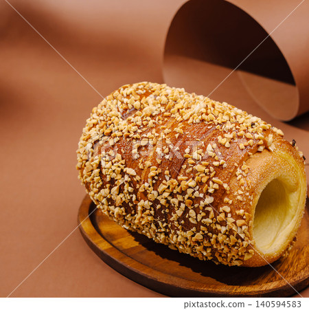 Traditional pastry with nuts sits on a wooden plate on a brown background Traditional pastry with nuts sits on a wooden plate on a brown background 140594583