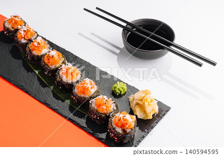 Sushi rolls with salmon served on a dark plate with wasabi and ginger Sushi rolls with salmon served on a dark plate with wasabi and ginger 140594595