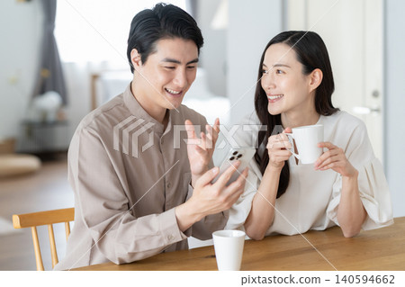 一對中年夫婦，在客廳裡看著智能手機 140594662