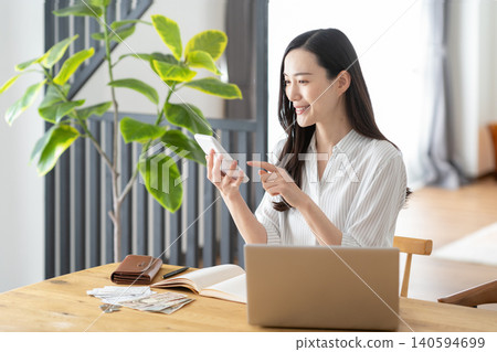 A woman keeping track of household expenses in the living room. 140594699