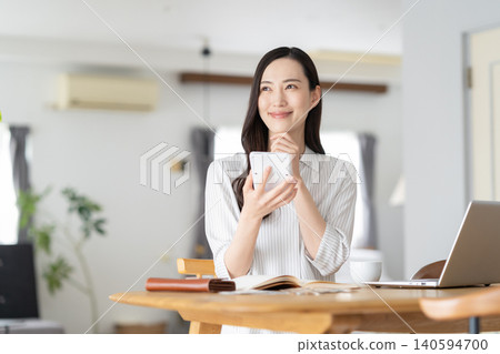 A woman keeping track of household expenses in the living room. A woman keeping track of household expenses in the living room. 140594700