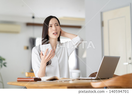 A woman keeping track of household expenses in the living room. A woman keeping track of household expenses in the living room. 140594701