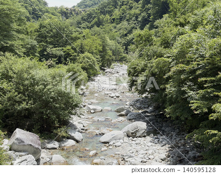 Yamanashi's Ojiragawa Valley: A clear stream flowing through a riverbed of white granite and lush green mountains. Yamanashi's Ojiragawa Valley: A clear stream flowing through a riverbed of white granite and lush green mountains. 140595128