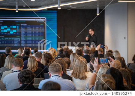 Audience attending business conference presentation with speaker and large screen for corporate event Audience attending business conference presentation with speaker and large screen for corporate event 140595274