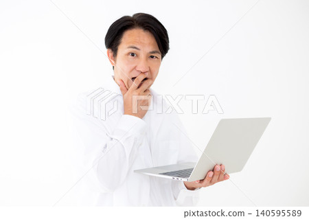 一位身穿白襯衫的中年男子,在白色背景前,一臉驚訝地看著筆記型電腦。 一位身穿白襯衫的中年男子,在白色背景前,一臉驚訝地看著筆記型電腦。 140595589