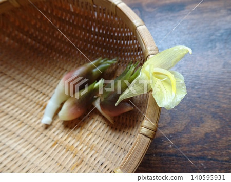 Fresh, blooming ginger leaves are placed on a bamboo basket with a wood grain background. Fresh, blooming ginger leaves are placed on a bamboo basket with a wood grain background. 140595931