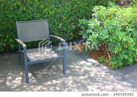A modern garden chair placed on a quiet outdoor terrace bathed in dappled sunlight. A modern garden chair placed on a quiet outdoor terrace bathed in dappled sunlight. 140595992