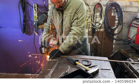 Professional repairman sawing metal construction with a circular saw at garage. Adult craftsman cuts iron using electric grind wheel and sparks flying around at workshop. Slow motion 140596034