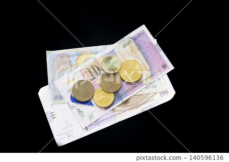 A pile of North Macedonian banknotes and coins are displayed against a black background. A pile of North Macedonian banknotes and coins are displayed against a black background. 140596136