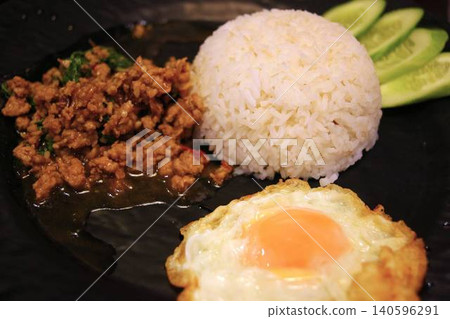 Traditional Thai minced pork gapao rice served with a fried egg and cucumber. Traditional Thai minced pork gapao rice served with a fried egg and cucumber. 140596291