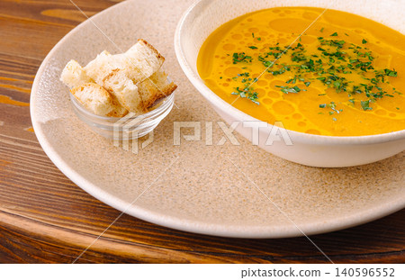 Warm pumpkin soup with croutons and parsley Warm pumpkin soup with croutons and parsley 140596552