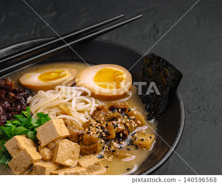 Japanese ramen noodles with tofu, egg, and seaweed in black bowl 140596568
