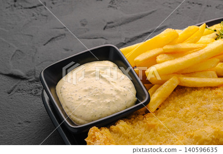 Fish and chips with tartar sauce on dark background Fish and chips with tartar sauce on dark background 140596635