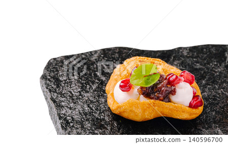 Gourmet profiterole appetizer with pomegranate seeds on slate Gourmet profiterole appetizer with pomegranate seeds on slate 140596700