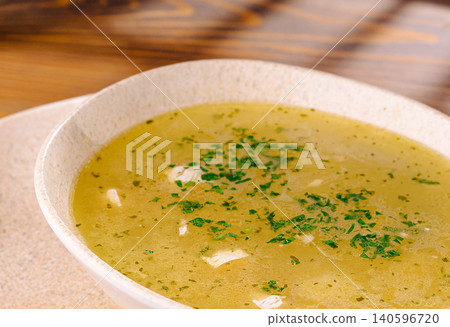 Golden chicken broth soup with fresh herbs 140596720