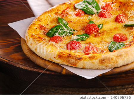 Pizza margherita on wooden table with basil and cherry tomatoes Pizza margherita on wooden table with basil and cherry tomatoes 140596726