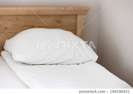 White pillow and duvet sit on a neatly made single bed White pillow and duvet sit on a neatly made single bed 140596931