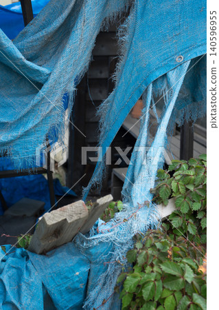 A deteriorated and torn blue tarp A deteriorated and torn blue tarp 140596955
